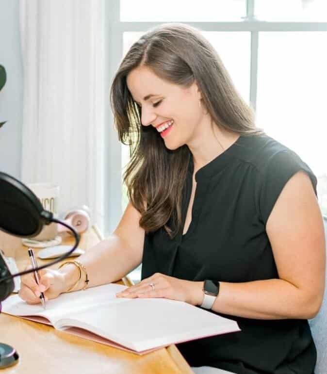 Noelle Tarr, founder of Well Minerals natural vitamins and supplements, smiles while writing in a notebook at a well-lit desk