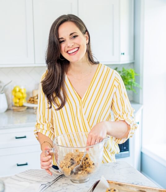 Noelle, owner of Well Minerals magnesium supplements, smiles as she mixes cookie dough in a clean and modern kitchen